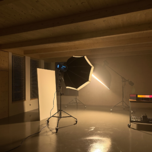 Modern photography studio in Luxembourg with a multi-light editorial setup — pine wood ceiling, large windows with wooden blinds, advanced lighting rig